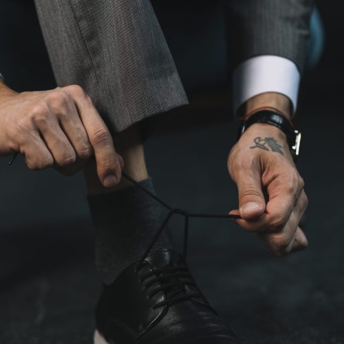low-section-businessman-s-hand-tying-shoelace