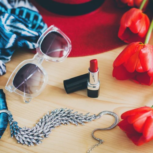 woman's accessories, red tulips, sunglasses, hat, lipstick, scarf, necklace, spring fashion trend, still life, view from above, details, vintage bohemian style,